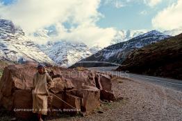 Image du Maroc Professionnelle de  Un berger berbère du haut Atlas vêtu par son djellaba colorée presque de la teinte de la pierre, s'incruste dans les roches de montagnes, comme un caméléon à proximité de l'Oukaimden, Samedi 22 Février 1987. (Photo / Abdeljalil Bounhar) 